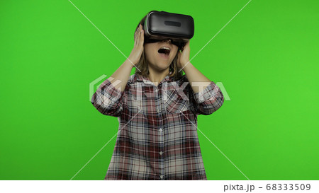 Girl using VR app helmet to play simulation scary game. Woman watching virtual reality 3D video Girl using VR app helmet to play simulation scary game. Woman watching virtual reality 3D video 68333509