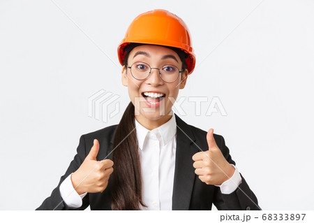 Excited happy female asian engineer, construction manager in safety helmet and business suit showing thumbs-up in rejoice, approve very good work, praise well done job, white background Excited happy female asian engineer, construction manager in safety helmet and business suit showing thumbs-up in rejoice, approve very good work, praise well done job, white background 68333897