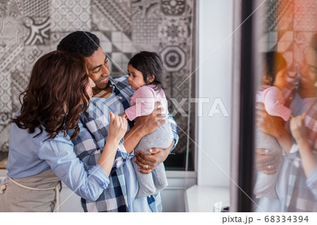 young cheerful mixed raced parents take care of their kid young cheerful mixed raced parents take care of their kid 68334394