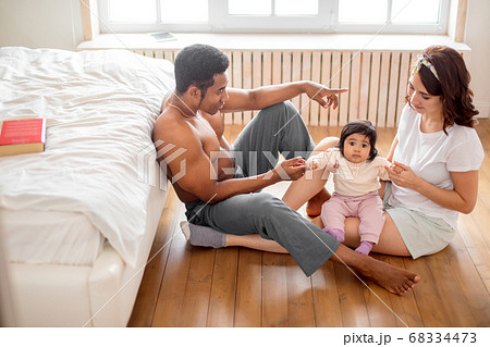 mixed raced friendly young family sitting on floor at home mixed raced friendly young family sitting on floor at home 68334473