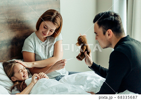 joyful father and mother with ill daughter on bed 68335687