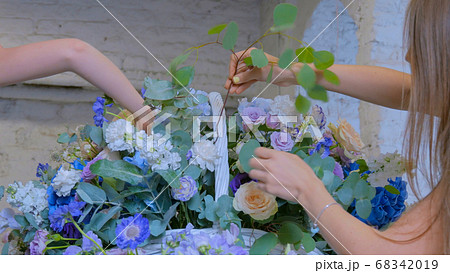 Two women florists making large floral basket with flowers at flower shop Two women florists making large floral basket with flowers at flower shop 68342019
