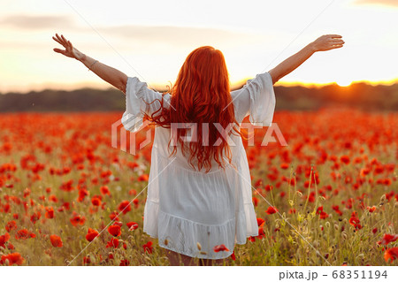 Happy redhead woman in white dress on field of 68351194