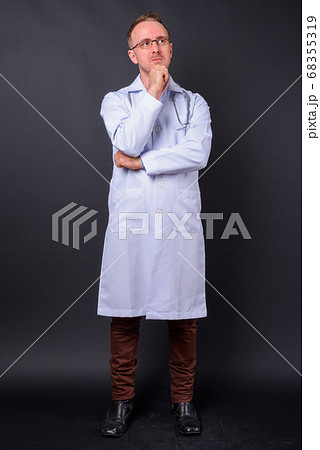 Handsome man doctor with blonde hair against black background 68355319