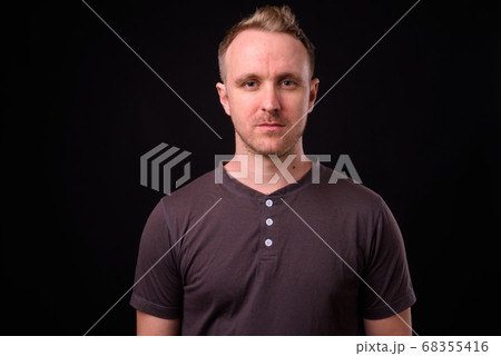 Handsome man with blonde hair against black background Handsome man with blonde hair against black background 68355416