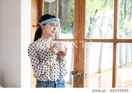 フェイスシールドをして窓辺に立つ女性 フェイスシールドをして窓辺に立つ女性 68356806
