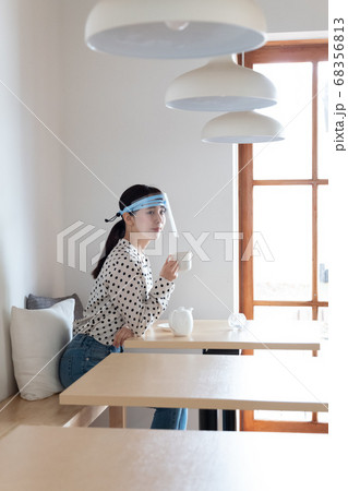 フェイスシールドをしてお茶を飲む女性 68356813