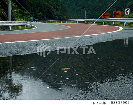 雨の降る山道のカーブと水たまり 雨の降る山道のカーブと水たまり 68357905