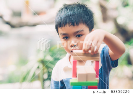 Asian young boy playing wooden block toy on table for creative and development with enjoy. Asian young boy playing wooden block toy on table for creative and development with enjoy. 68359226