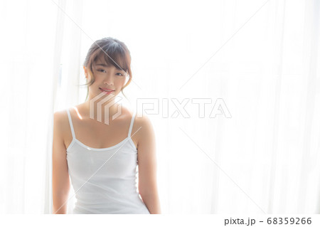 Portrait of beautiful young asian woman standing the window and smile while wake up with sunrise. Portrait of beautiful young asian woman standing the window and smile while wake up with sunrise. 68359266