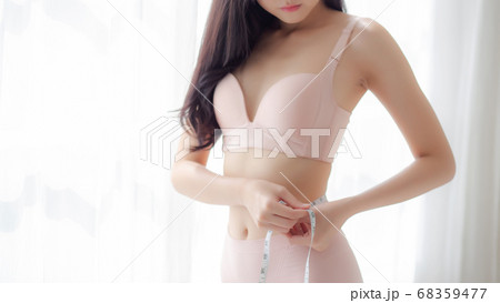 Beautiful young asian woman sexy body slim measuring abdomen for control weight loss in the room. 68359477