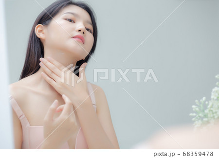 Beautiful sexy young asian woman looking mirror applying cream on neck and message. Beautiful sexy young asian woman looking mirror applying cream on neck and message. 68359478