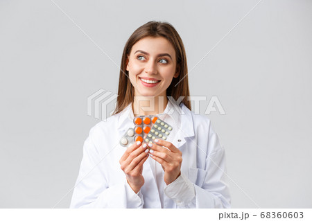 Pharmacy, healthcare workers, insurance and hospitals concept. Thoughtful smiling and pleased female doctor in white scrubs, look away thinking, holding medicine, pills or vitamins 68360603