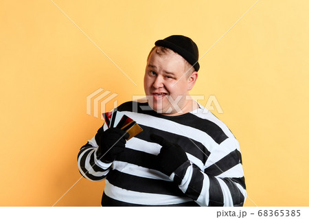 plump thief pointing at credit cards 68365385