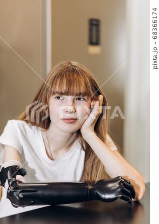 attractive pensive girl with amputated arm sitting at the table 68366174