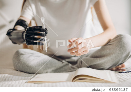 disabled girl tries to hold a pen with an artificial arm disabled girl tries to hold a pen with an artificial arm 68366187