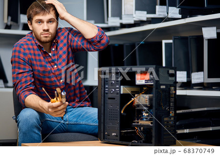 thoughtful confused bearded guy sitting near the broken system unit thoughtful confused bearded guy sitting near the broken system unit 68370749