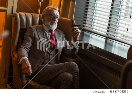 Serene concentrated mature male architector with grey-haired beard smoking cigar Serene concentrated mature male architector with grey-haired beard smoking cigar 68370895