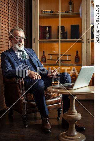Senior dramatist looking at laptop, creating novel while sitting Senior dramatist looking at laptop, creating novel while sitting 68373268