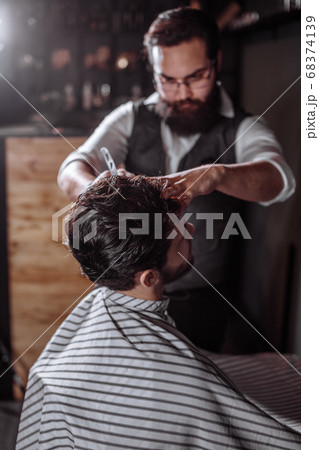 Skillful barber. Young man getting an old-fashioned shave with s Skillful barber. Young man getting an old-fashioned shave with s 68374139