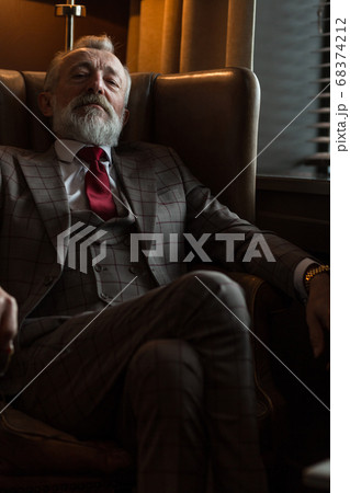 Toned retro styled portrait of businessman sitting in armchair at office Toned retro styled portrait of businessman sitting in armchair at office 68374212