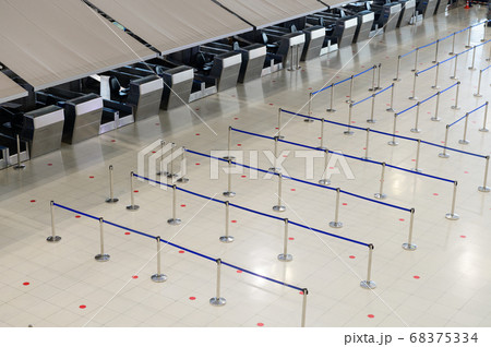 Empty airport check-in counter hall with crowd control barriers 68375334