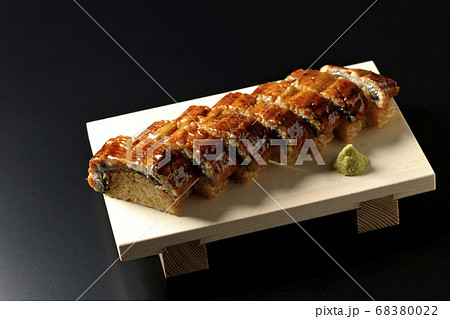 寿司下駄に盛り付けられた鰻の姿寿司とワサビ（黒背景） 68380022