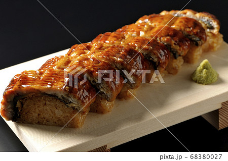 寿司下駄に盛り付けられた鰻の姿寿司とワサビ（黒背景） 68380027