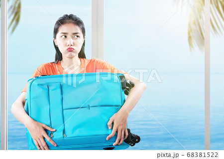 Asian woman carrying a suitcase on the resort Asian woman carrying a suitcase on the resort 68381522