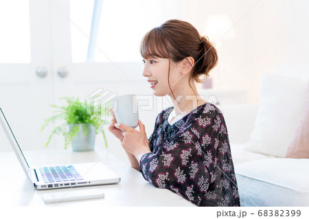 リビングでズームで友達と話をしながらお茶を飲む若い女性 リビングでズームで友達と話をしながらお茶を飲む若い女性 68382399