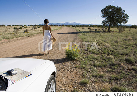Native American woman in sun dress driving a white convertible sports car on desert dirt 68384668