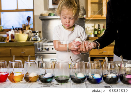 3 year old girl coloring easter eggs at home with her mother 3 year old girl coloring easter eggs at home with her mother 68385359