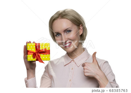 Happy smiling blond woman holding gift box and making ok gesture. Happy smiling blond woman holding gift box and making ok gesture. 68385763