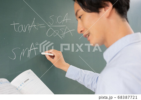 黒板に数式を書く若い男性教師　手にピント 68387721