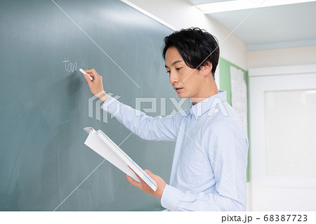 黒板に数式を書く若い男性教師 68387723