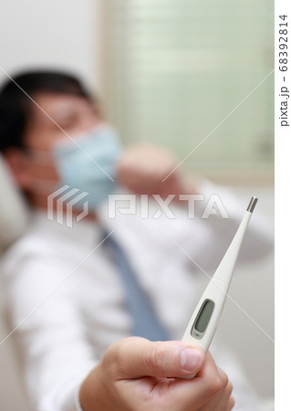 マスクをして体温を測る体調不良のビジネスマン 68392814