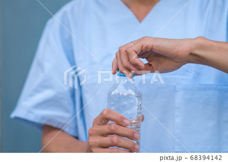 Cropped image of a doctor's hand opening a plastic bottle of water Cropped image of a doctor's hand opening a plastic bottle of water 68394142