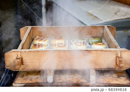 信州の宿場町のおやき屋の店先で蒸しあがった、焼き目のついた白とよもぎの緑色のおやき、立ち昇る湯気。 信州の宿場町のおやき屋の店先で蒸しあがった、焼き目のついた白とよもぎの緑色のおやき、立ち昇る湯気。 68394616