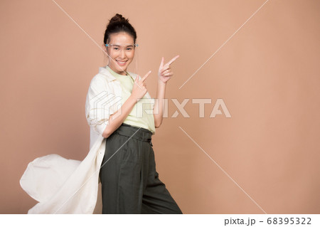 フェースシールドを付けて茶色BGの前でポーズする若い女性モデル 68395322