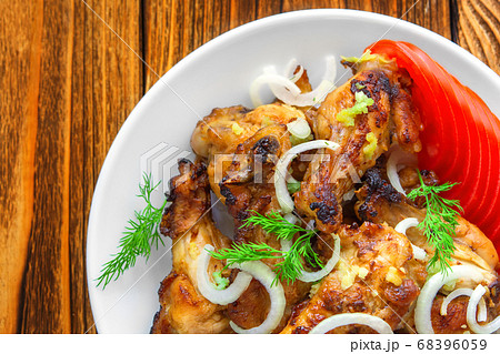 Fried chicken wings close-up, with fresh tomatoes, onions, dill, garlic on a wooden background. View from above. The concept meat food. Fried chicken wings close-up, with fresh tomatoes, onions, dill, garlic on a wooden background. View from above. The concept meat food. 68396059