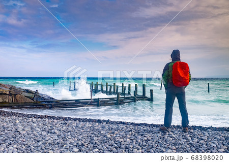 Man tourist watch how waves crash into pier 68398020