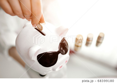 women's hand fills piggy bank from stacks of coins standing next to women's hand fills piggy bank from stacks of coins standing next to 68399180