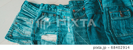Jeans shorts layered by shades of blue indigo dye. Different styles of distressed denim fashion textile fabric banner panoramic 68402914