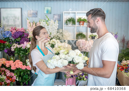 Bearded male buying white flowers from smiling female florist 68410368