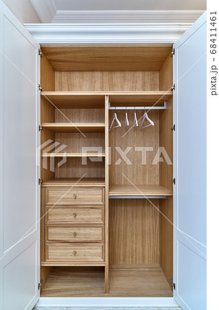 White wardrobe with wooden drawers and shelves. Wooden filling of wardrobe and white clothes hangers White wardrobe with wooden drawers and shelves. Wooden filling of wardrobe and white clothes hangers 68411461