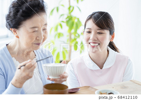 介護イメージ 食事をするシニア女性と介助する介護士 介護イメージ 食事をするシニア女性と介助する介護士 68412110