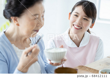 介護イメージ　食事をするシニア女性と介助する介護士 68412111