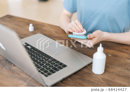 Close-up of hands of unrecognizable woman wiping with antibacterial sanitizer display of cell phone Close-up of hands of unrecognizable woman wiping with antibacterial sanitizer display of cell phone 68414427