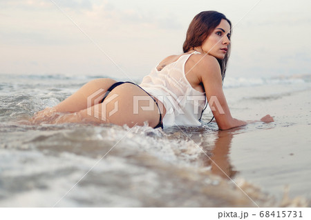 Sexy woman posing on beach near the sea at sunrise - Stock Photo