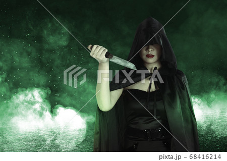 Asian witch woman with black cloak holding a knife Asian witch woman with black cloak holding a knife 68416214